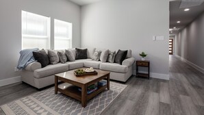 Una sala de estar moderna con un sofá modular, una mesa de centro de madera y una alfombra estampada.