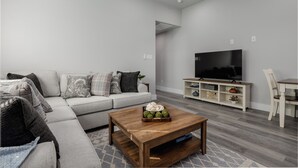 Una sala moderna con un sofá, una mesa de centro, televisor y un comedor.