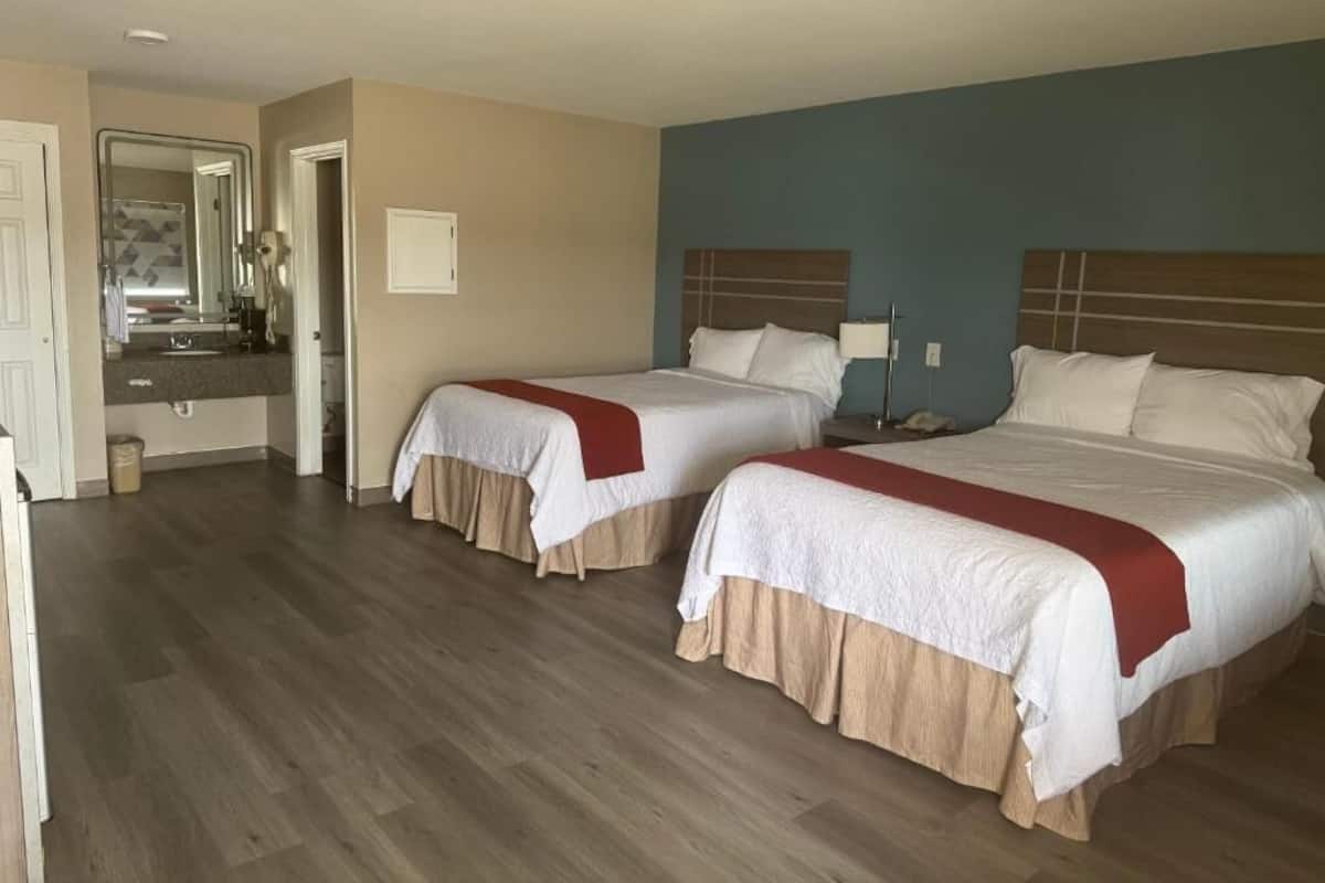 Habitación de hotel con dos camas, un baño y un pasillo.
