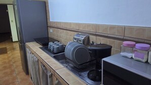 Eine Küche mit Kühlschrank, Herd und Mikrowelle. Handtücher hängen, und es gibt ein Spülbecken.