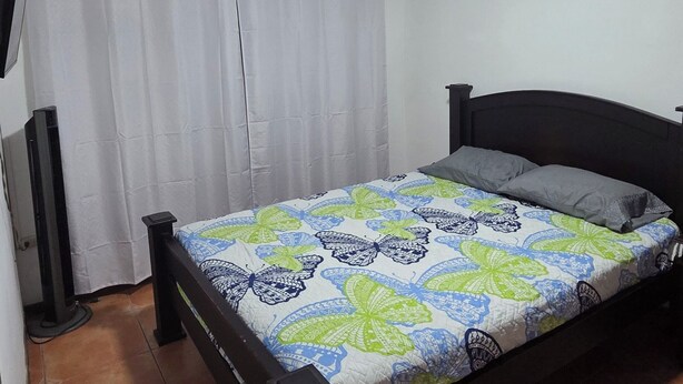 Ein Schlafzimmer mit Bett, Fernseher und Deckenleuchte.