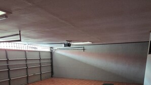 Ein geräumiges Dachzimmer mit schrägen Wänden, einem großen Fenster und einer Metalldachgarage.