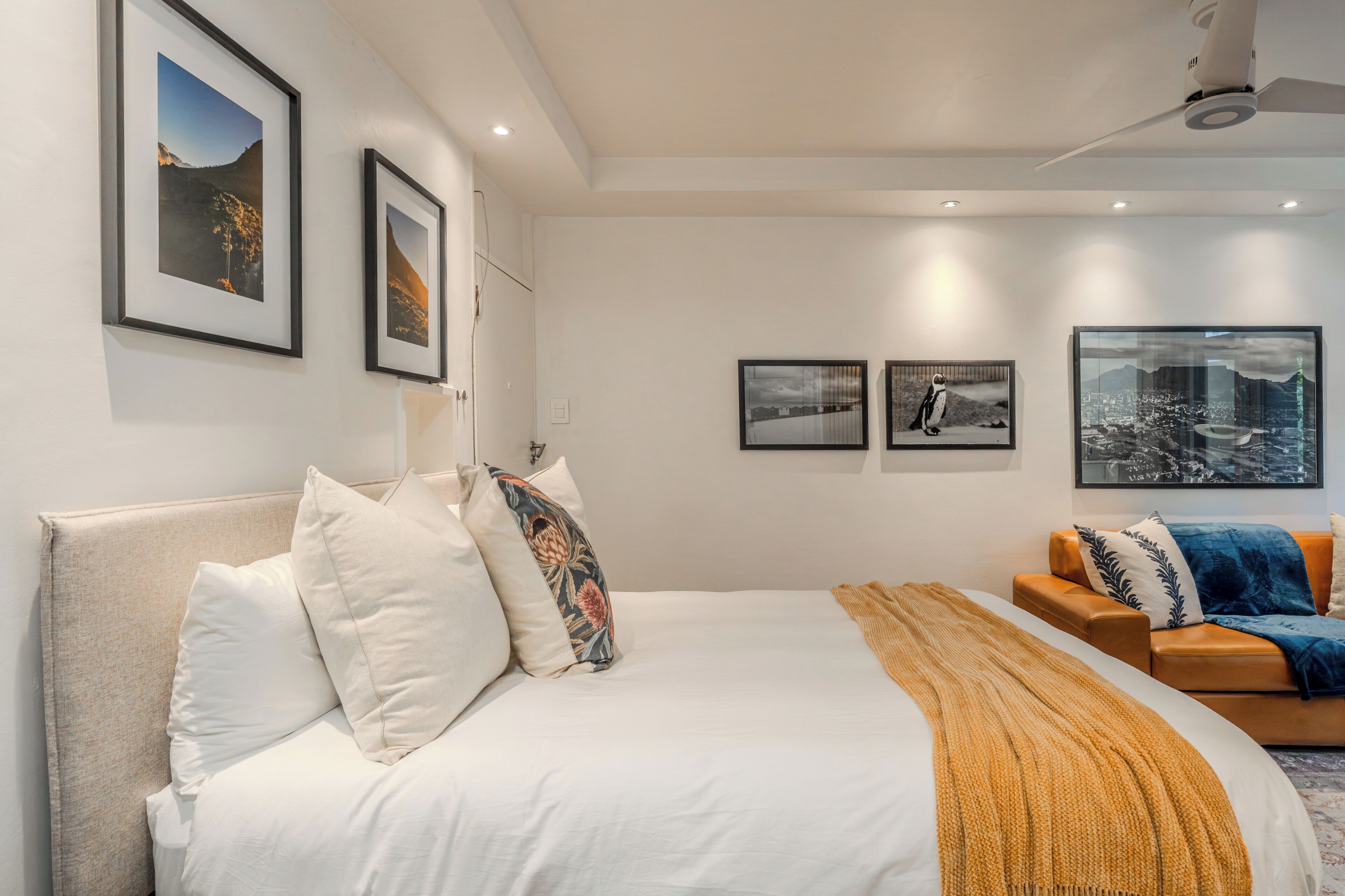 A modern bedroom with a large bed, a sofa, and framed pictures on the walls.
