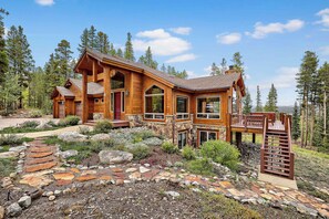A wooden cabin with a stone foundation, multiple windows, and a deck. - Morning View Lodge | Mountain Retreat with Hot Tub (Breckenridge)