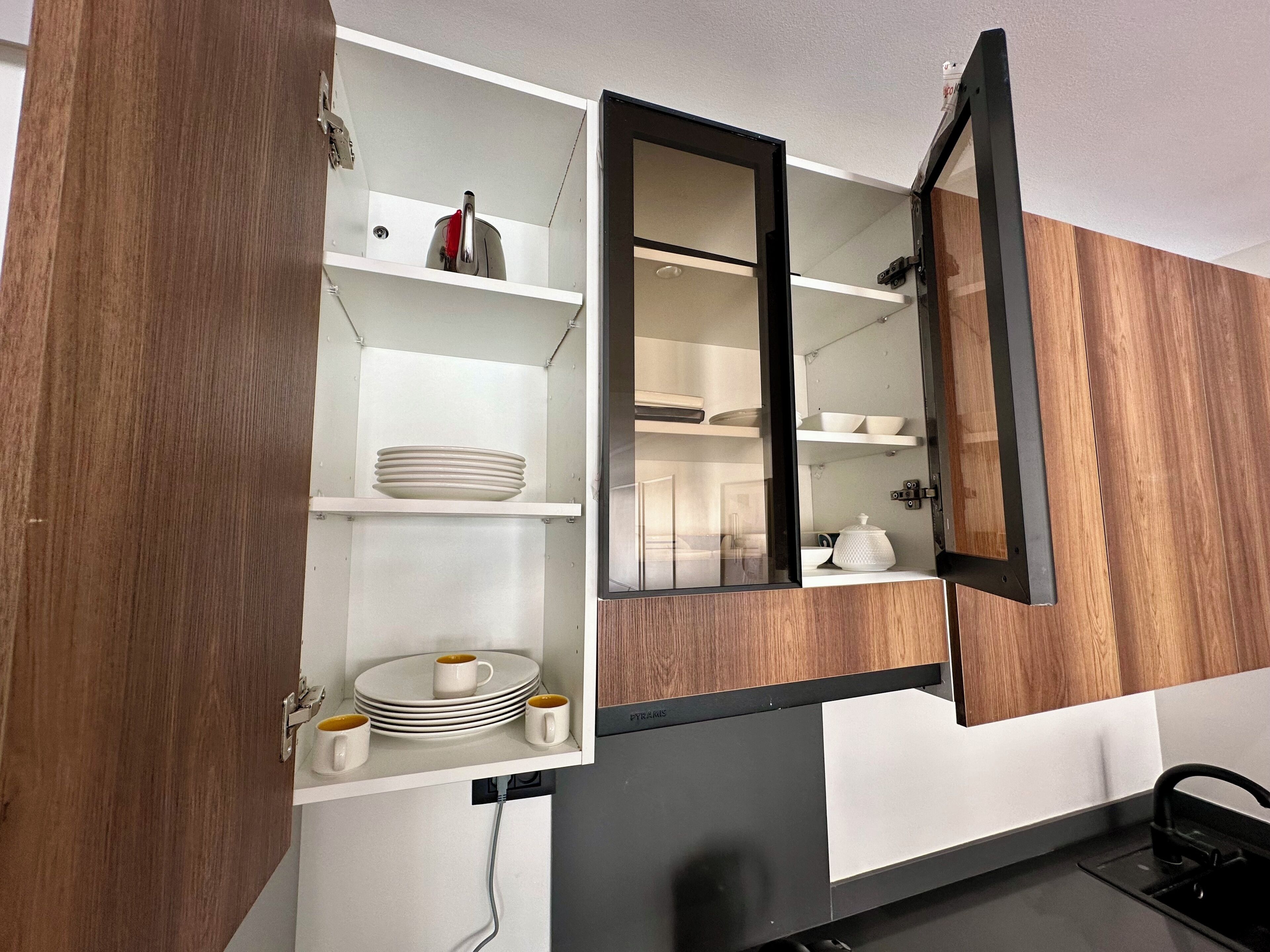A kitchen with a built-in microwave, a sink, and a cabinet with a mirror.