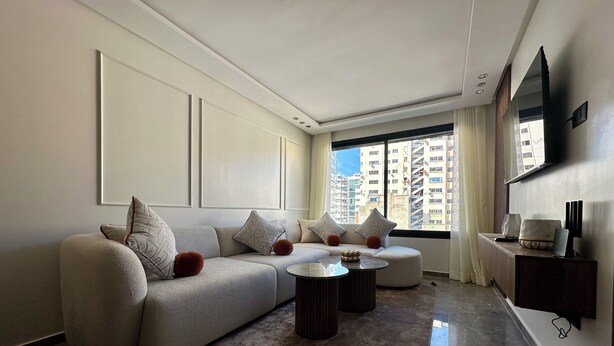 Una sala de estar moderna con un sofá modular, una mesa de centro y un televisor montado en la pared.