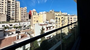 Un edificio de gran altura con varios balcones y antenas parabólicas, visto desde una ventana con cielo despejado.