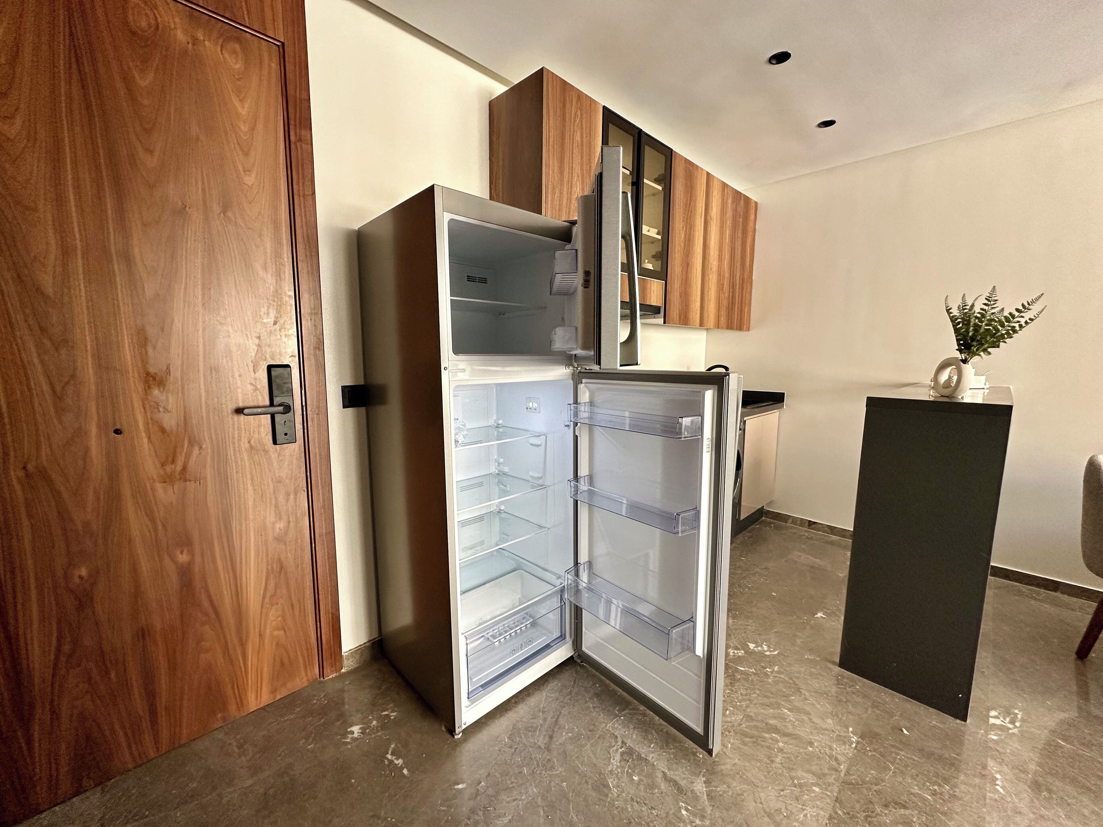 Una cocina moderna con refrigerador integrado, armarios de madera y piso de mármol.