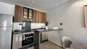 Una cocina moderna con horno integrado, refrigerador de acero inoxidable, armarios de madera y encimera de mármol.