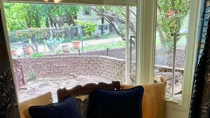 Un siège de fenêtre agrémenté de coussins, un mur en briques et une vue sur le jardin.