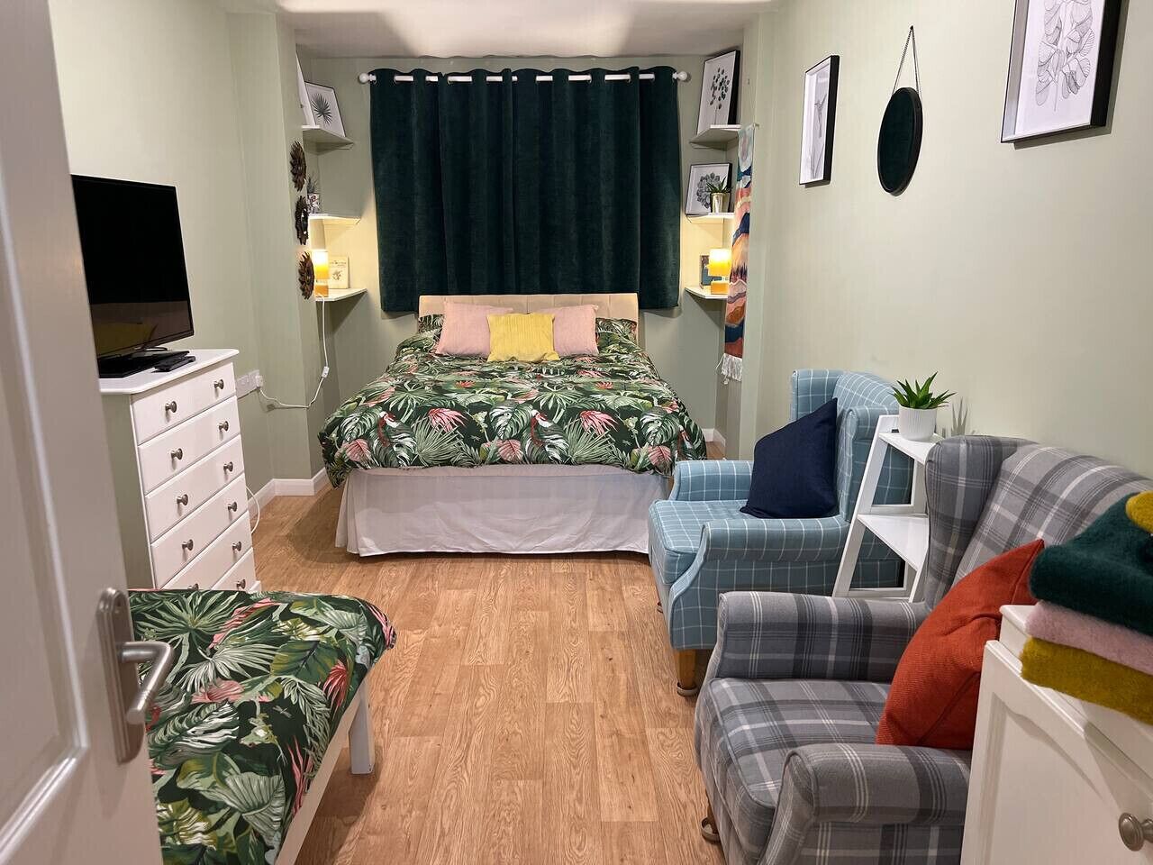 A bedroom with a bed, a desk, a chair, and a sofa.