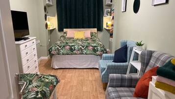 A bedroom with a bed, a desk, a chair, and a sofa.