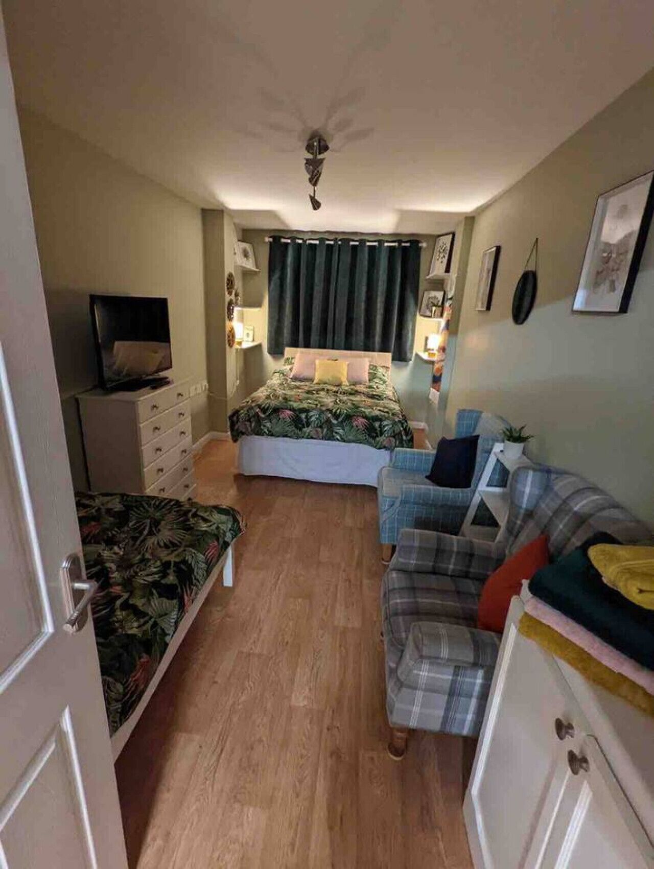 Ein Schlafzimmer mit einem Bett, einem Fernseher, einer Kommode, einem Sofa und einem Deckenventilator.