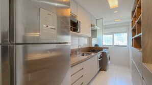 A modern kitchen with stainless steel appliances, a built-in microwave, and a window providing natural light. - Ipanema 2 Suites Ocean View 1min to Beach (Rio de Janeiro)