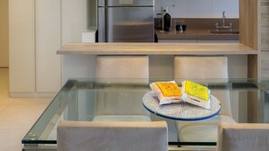 A modern kitchen with a glass dining table, stainless steel appliances, and a pendant light. - Ipanema 2 Suites Ocean View 1min to Beach (Rio de Janeiro)