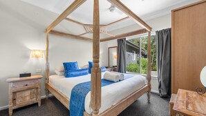 Ein Himmelsbett mit Vorhängen und Blick ins Freie, ein Nachttisch und ein Holzschrank.