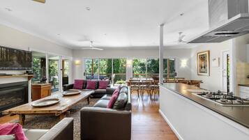 A spacious living area with a fireplace, a dining table, and a kitchen with a gas stove.