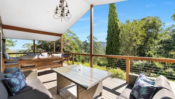 A covered outdoor seating area with a table, benches, and a view of the surrounding landscape.