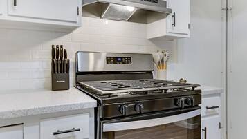 A kitchen with white cabinetry, a stainless steel stove, and a built-in oven.