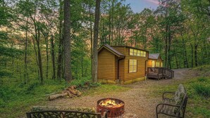 Eine Hütte mit Feuerstelle und Bänken in einer Waldlandschaft.