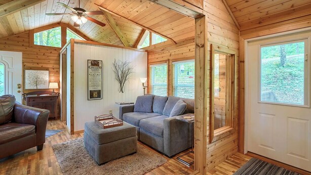 Ein gemütliches Holzinnere mit Sofa, Hocker und Deckenventilator.