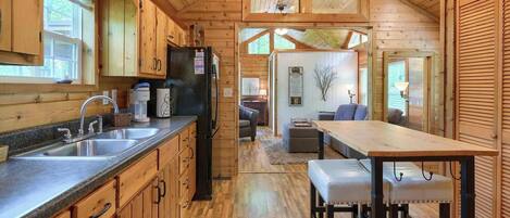 L’intérieur d’une cabane en bois comprend une cuisine, un coin repas et un salon.