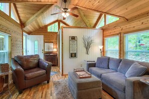A log cabin interior with a brown leather sofa, a gray sofa, a wooden ceiling with a fan, and a window with blinds. - Lo Lo’s Place Cedar Cottage Near Old Man’s Cave (Logan)