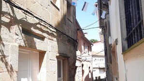 Une rue étroite bordée d’immeubles en pierre, avec une porte bien visible et une fenêtre ornée d’un drapeau.