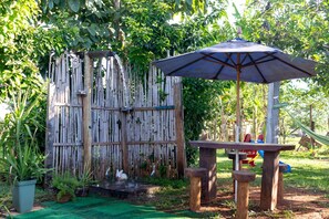 A bamboo fence, a wooden table with an umbrella, and a small water feature.