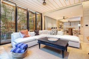 Ein modernes Wohnzimmer mit einem Ecksofa, einem Couchtisch und einem Essbereich im Hintergrund.