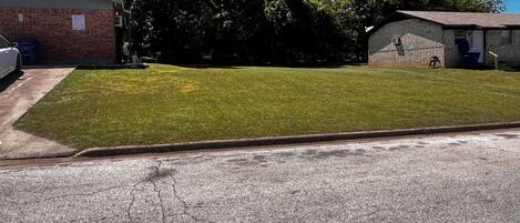 A residential area with a well-maintained lawn, a brick building, and a garage.
