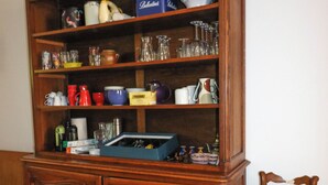 A wooden cabinet with shelves containing various kitchen items.