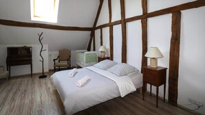 A bedroom with a bed, two bedside tables with lamps, a chair, a desk, and a radiator.
