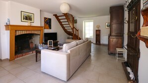 A living room with a fireplace, a sofa, a staircase, and a wooden cabinet.