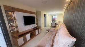 A modern living room with a flat-screen TV, a sofa, and a wooden entertainment unit. - Atlantic View 309 - Elegance and Comfort on the Intermares Beachfront for 5 people (Cabedelo)