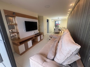 Ein modernes Wohnzimmer mit Fernseher, einer Couch und einer Holzunterhaltungseinheit.