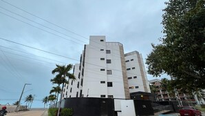 A multi-story building with a modern architectural design, featuring a prominent entrance with a black gate and a visible parking area. - Atlantic View 309 - Elegance and Comfort on the Intermares Beachfront for 5 people (Cabedelo)