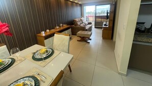 A modern living room with a dining area, a sofa, and a TV. - Atlantic View 309 - Elegance and Comfort on the Intermares Beachfront for 5 people (Cabedelo)