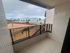 Ein Balkon mit Blick auf den Strand, mit Kacheln an den Wänden und einem Metallgeländer.