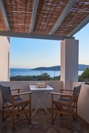 A balcony with a table and two chairs, overlooking a scenic view of the sea and hills. - Velithra Maisonette, Divine Sea Views, Furnished Terrace, Antiparos (Antiparos)