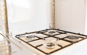 A kitchen with a gas stove, white cabinets, and a tiled backsplash. - [Olbia] House with Wi-fi Parking near waterfront (Olbia)