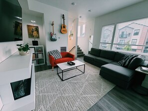 Ein modernes Wohnzimmer mit einer Couch, einem roten Sessel, einem Couchtisch und einer Gitarre an der Wand.
