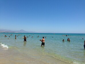 A beach with clear water and people swimming and playing. - ESTUDIO PLAYA MUCHAVISTA by Interhome (El Campello/Villajoyosa)