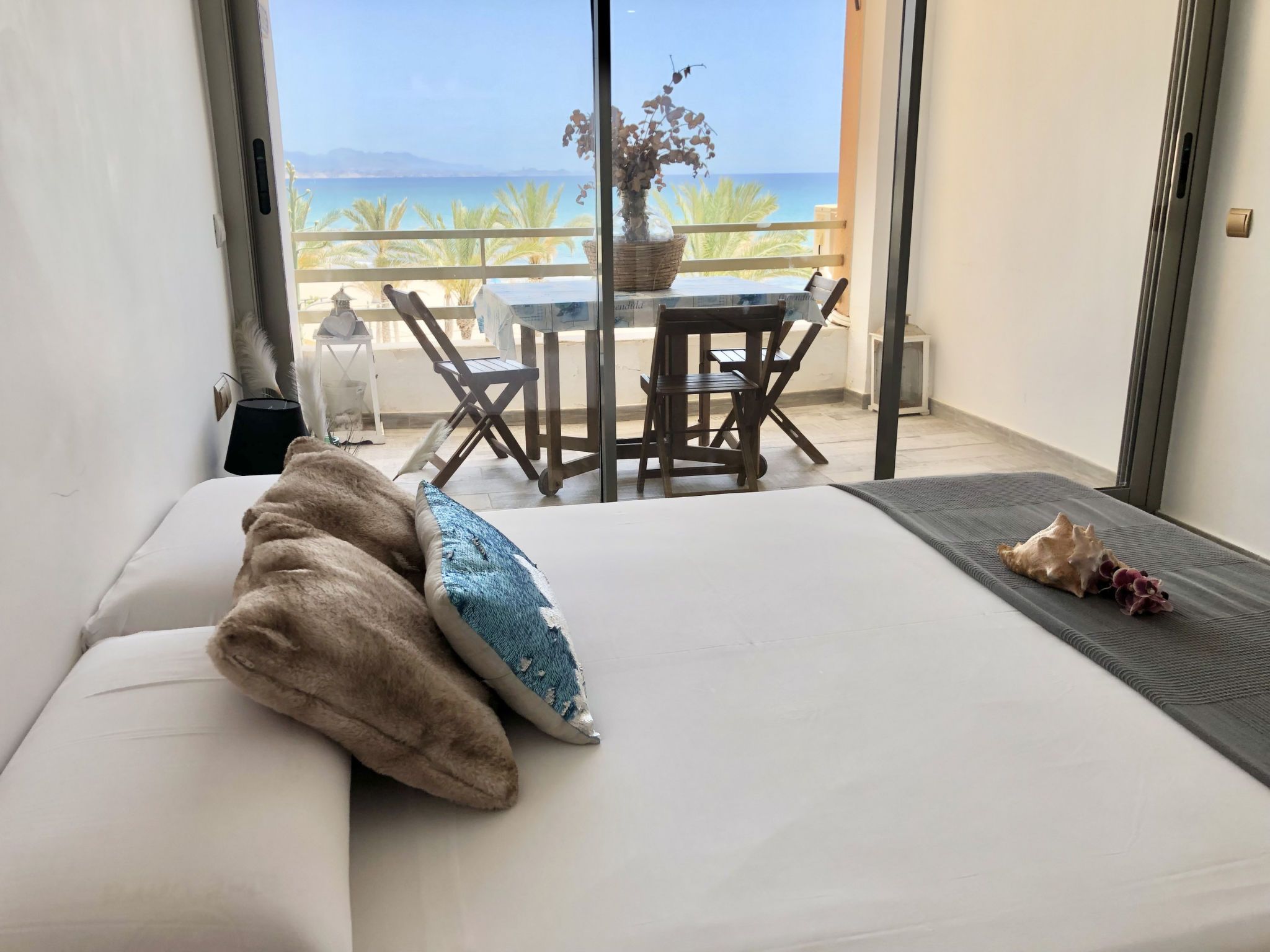 Un dormitorio con cama, una mesita con sillas y vista al mar.