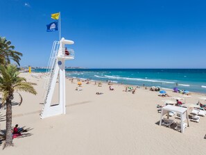 A lifeguard tower on a beach with clear skies, palm trees, and people sunbathing. - ESTUDIO PLAYA POSTIGUET by Interhome (Alicante)