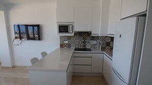A modern kitchen with white cabinetry, a built-in microwave, and a tiled backsplash. - ESTUDIO PLAYA POSTIGUET by Interhome (Alicante)