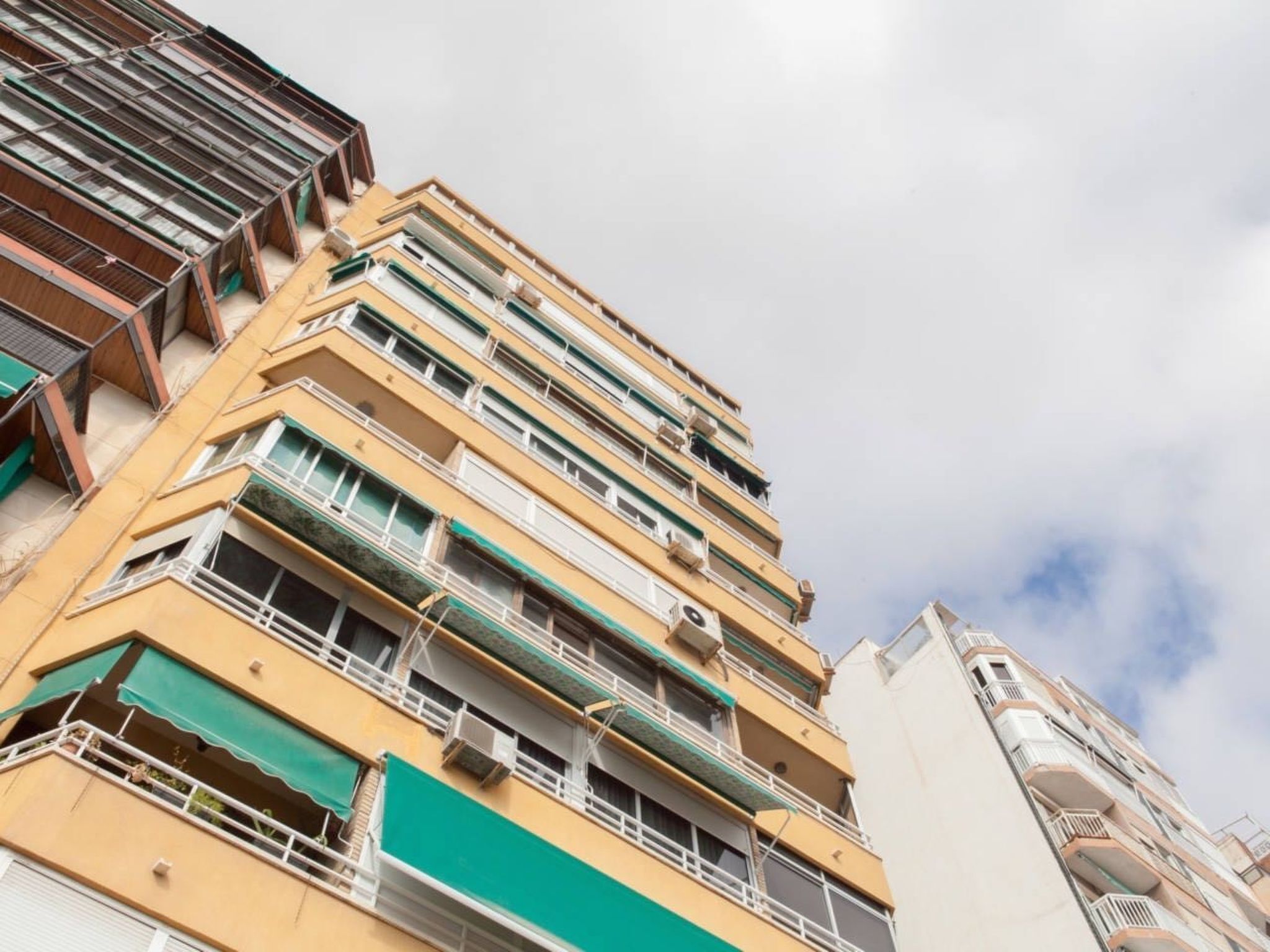 Un edificio de varios pisos con balcones y unidades de aire acondicionado.