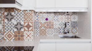 A kitchen with white cabinets and a variety of patterned tiles on the backsplash. - ESTUDIO PLAYA POSTIGUET by Interhome (Alicante)