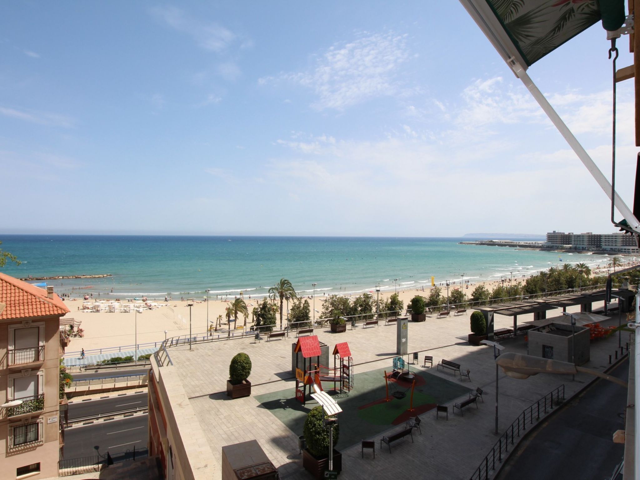 Vista de uma praia com um parquinho e um edifício ao primeiro plano.