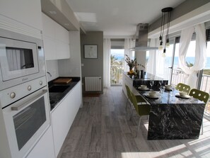 A modern kitchen with a central island, white cabinetry, and a view of the sea through large windows. - APARTAMENTO MEDITERRANEO by Interhome (El Campello/Villajoyosa)